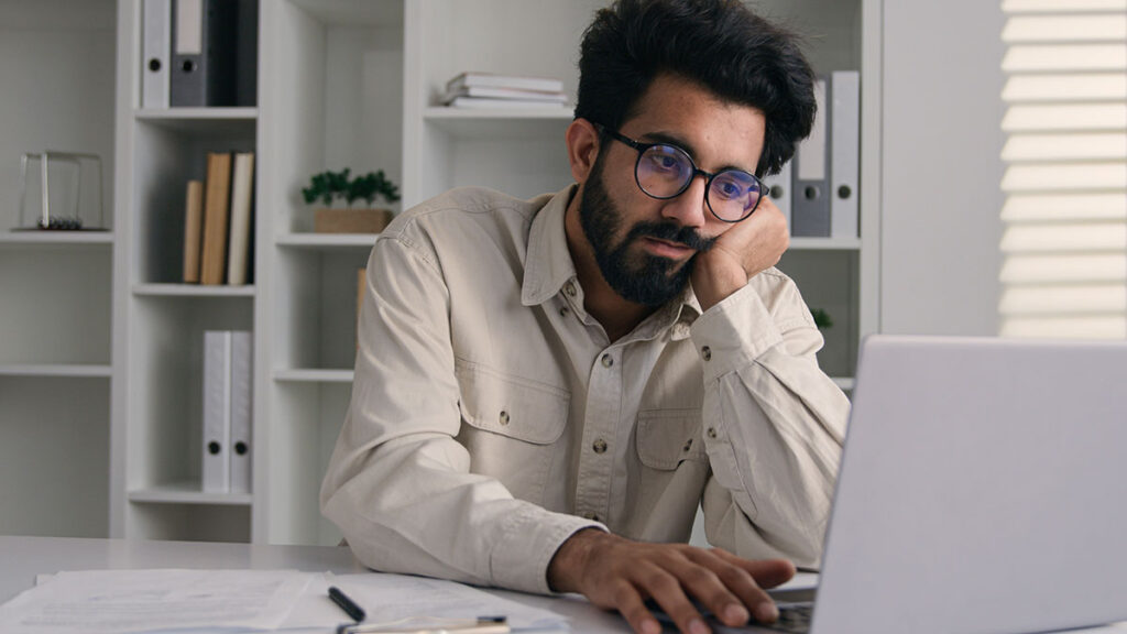 man low energy and slouching while working on computer
